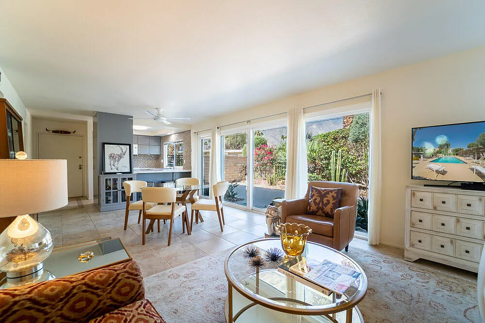 Living room with large windows, dining area, and a cozy seating arrangement with a view of a garden.