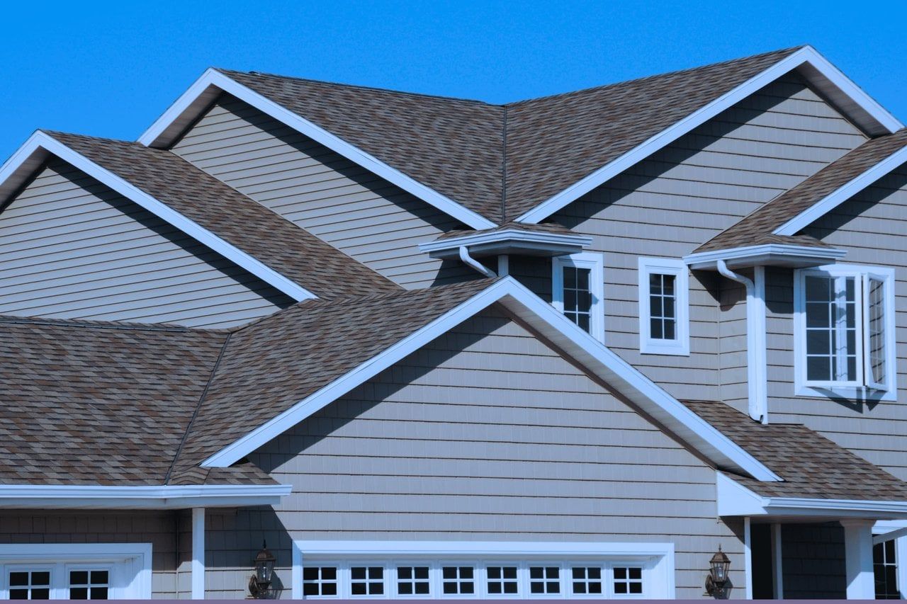 House exterior with brown roof, light gray siding, and white trim.