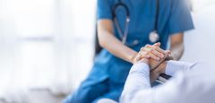 A nurse is holding the hand of a patient.