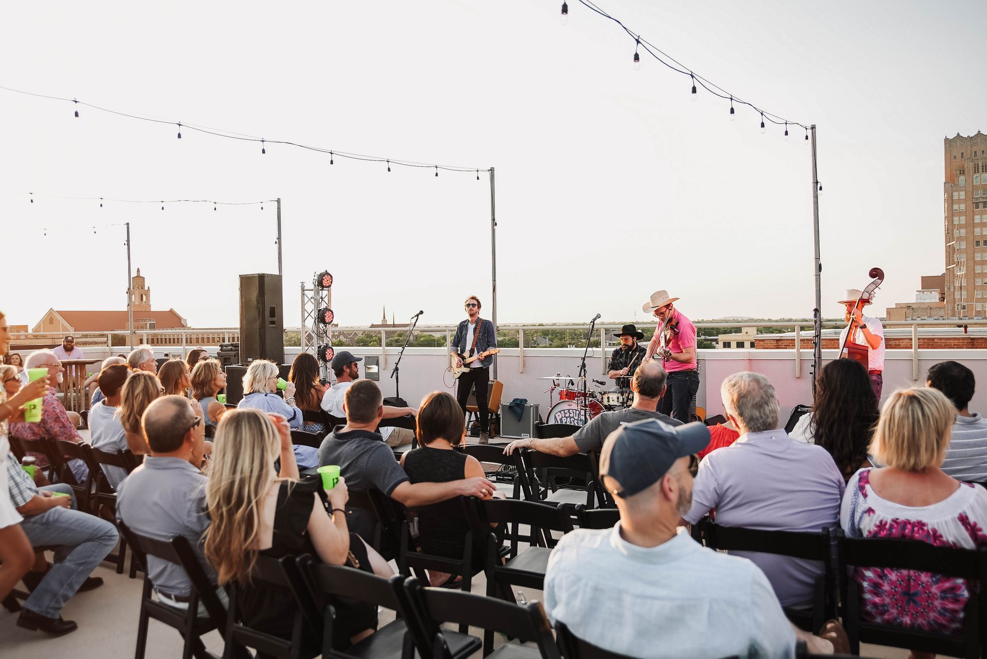A group of people are sitting in chairs watching a band perform on a stage.