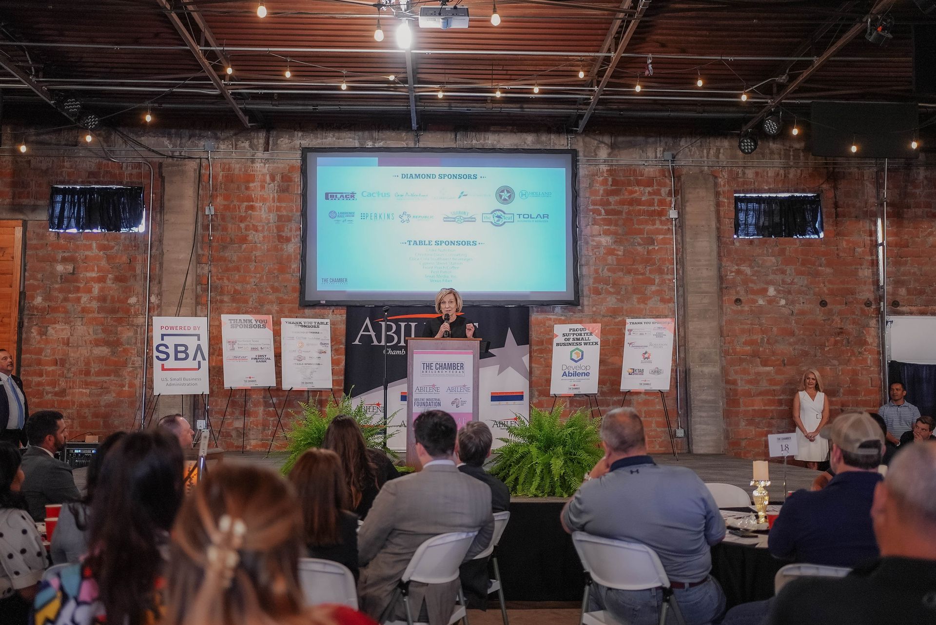 A group of people are sitting in front of a large screen.