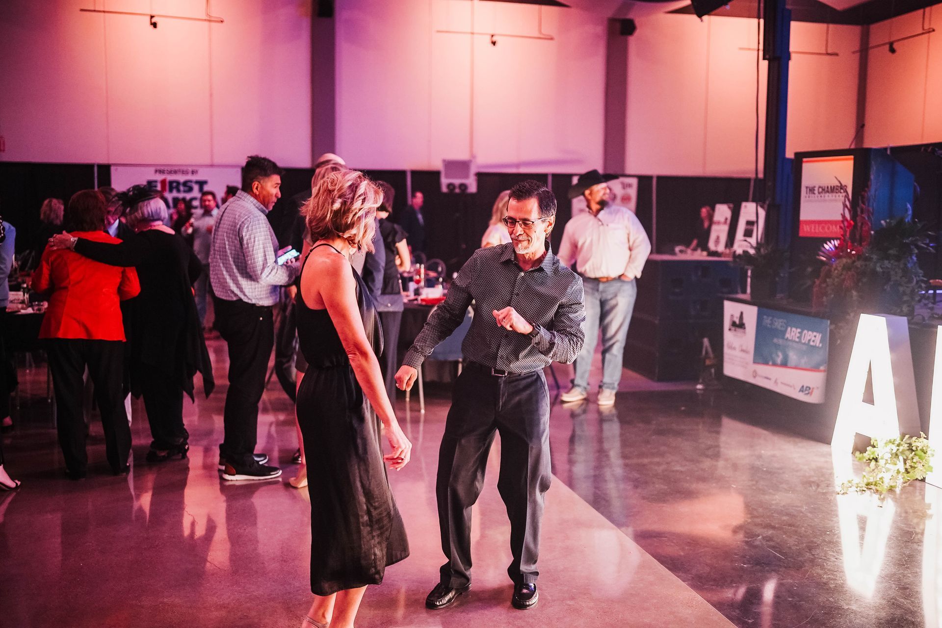 A man and a woman are dancing on a dance floor at a party.