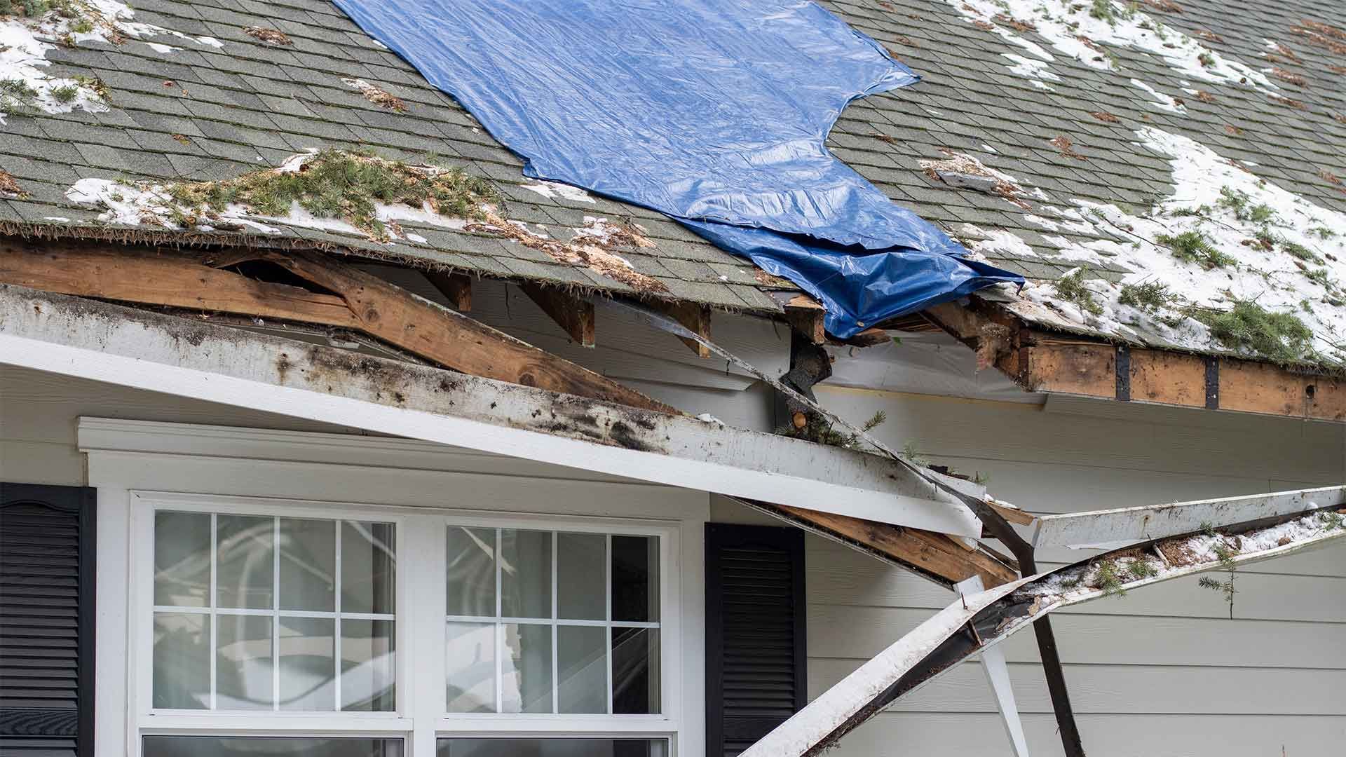 A blue tarp is covering the roof of a house.