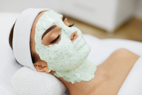 Een vrouw ligt op bed met een groen masker op haar gezicht.