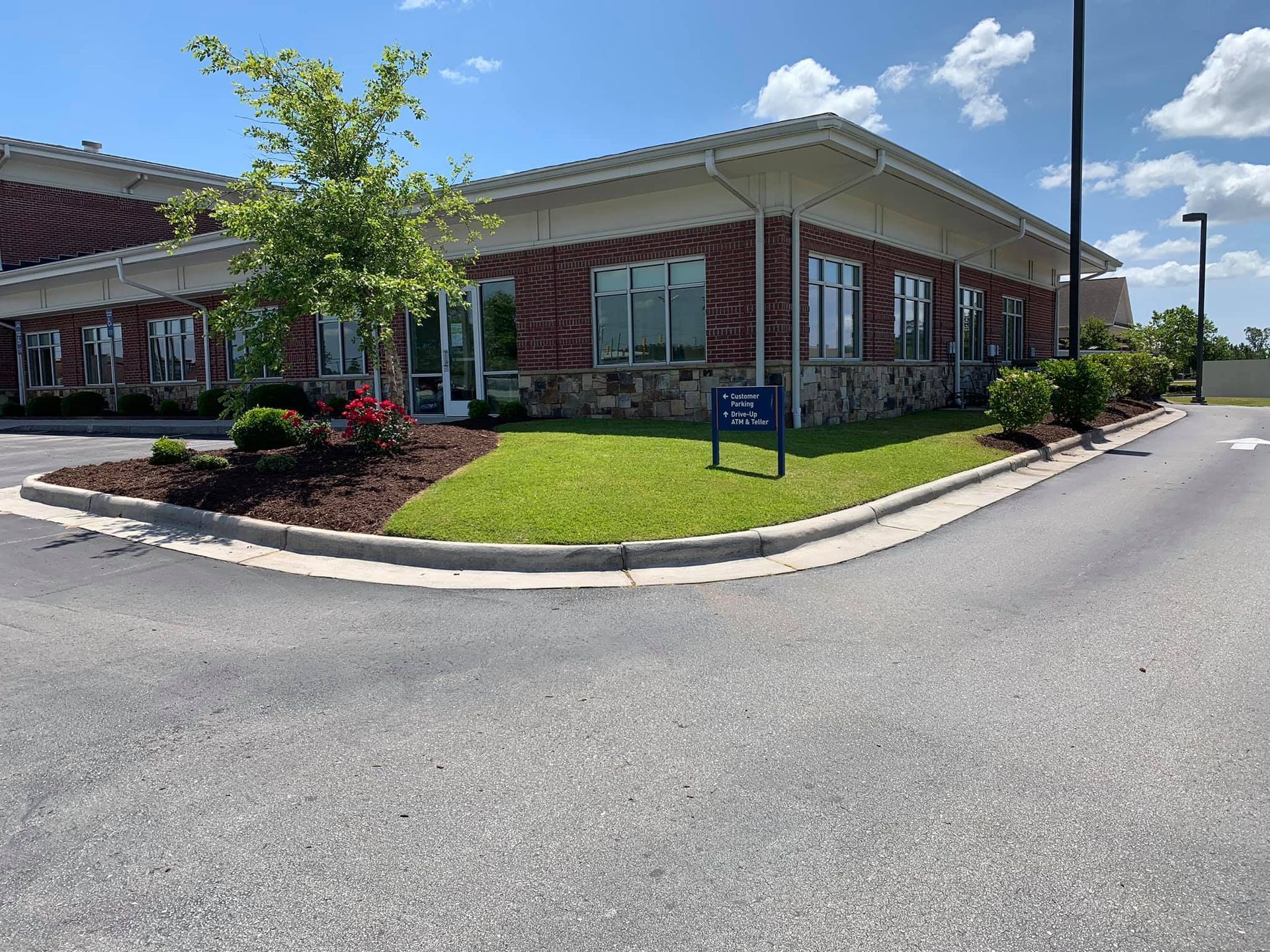 A large brick building is sitting on the corner of a street with lush grass.