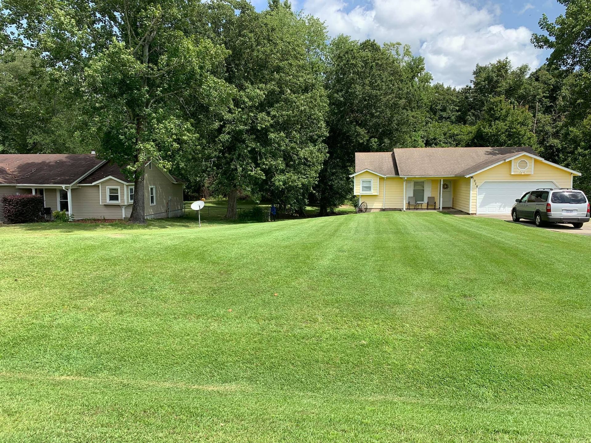 A house with a large lawn in front of it and a car parked in front of it.
