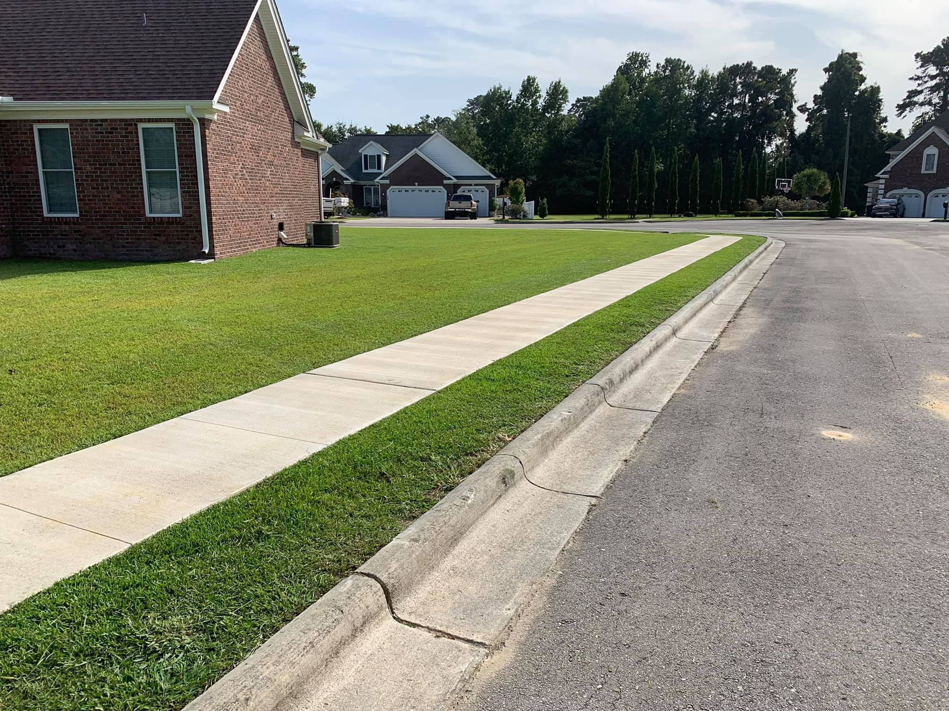 A brick house sits on the corner of a residential street