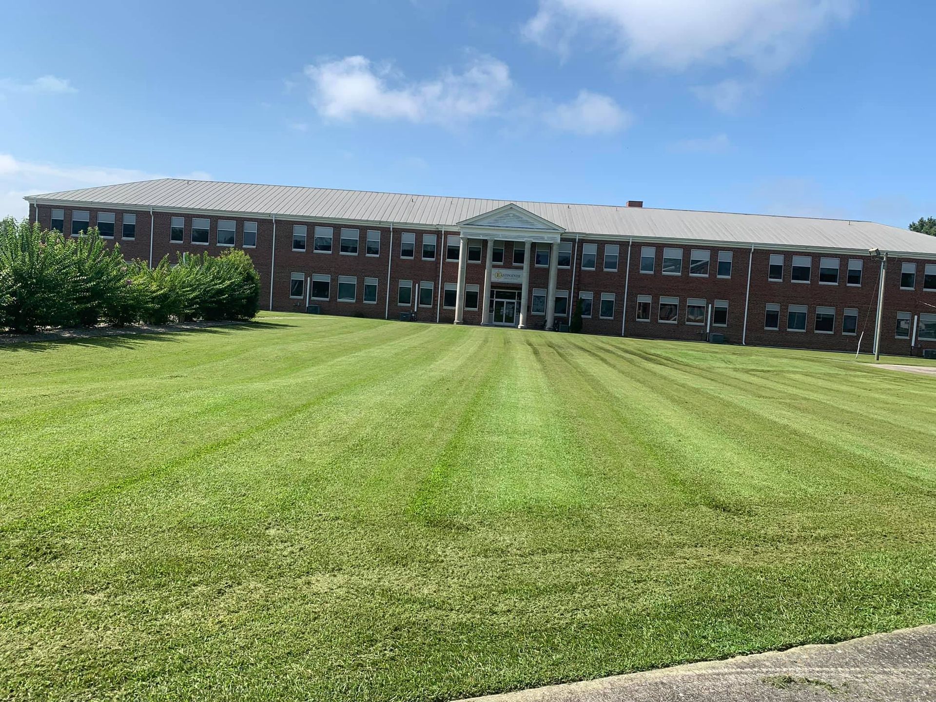A large brick building with a lush green lawn in front of it.