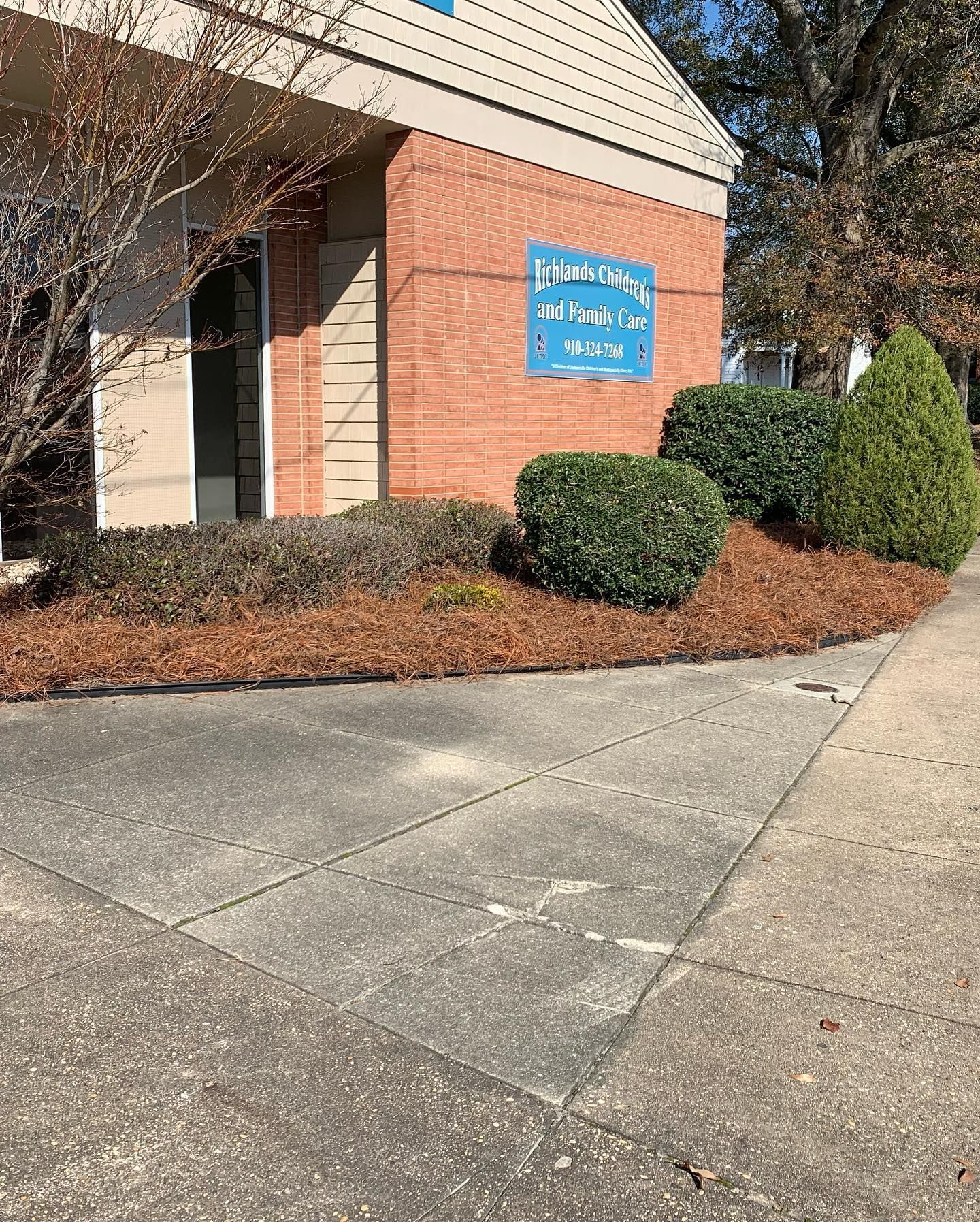 A brick building with a sign on the side of it and a sidewalk in front of it.