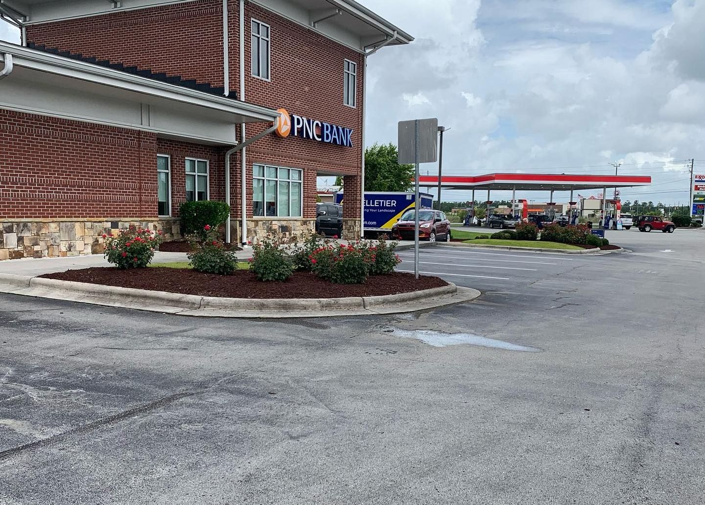 A brick building with a landscaped bed areas bordering parking stalls.