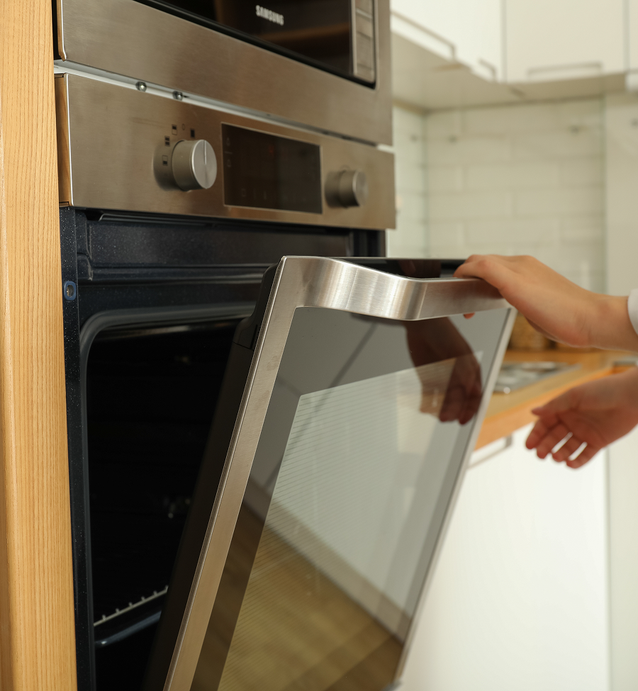 A person is opening a stainless steel oven door
