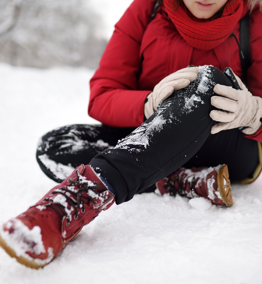 A woman in a red jacket is kneeling in the snow