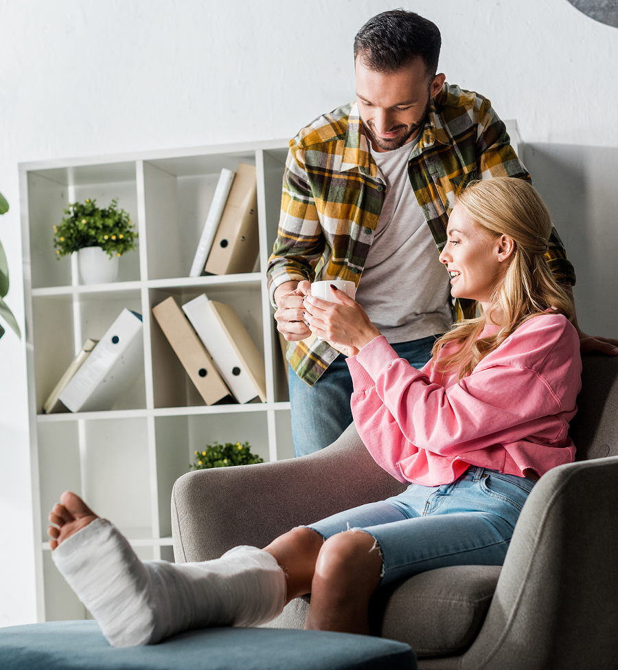 A woman with a cast on her leg is sitting in a chair next to a man.