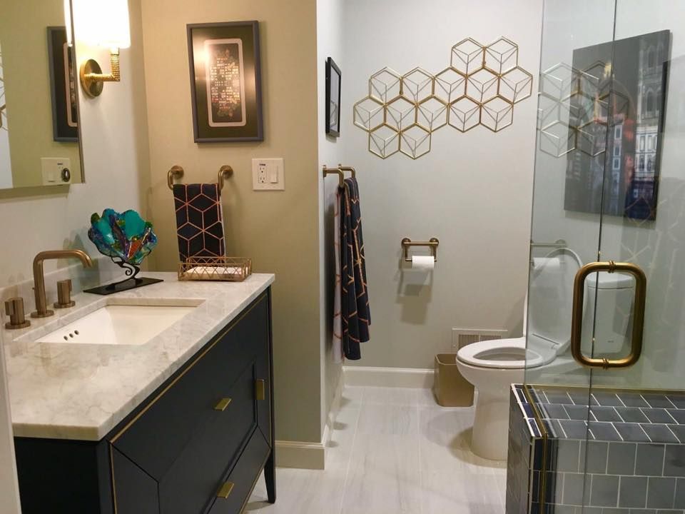Bathroom with black vanity, gold fixtures, white sink, and honeycomb wall decor.