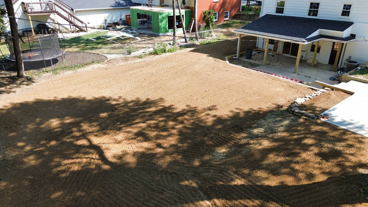 An elevated view of a cleared, level backyard of brown soil next to a house with a newly constructed wooden porch.