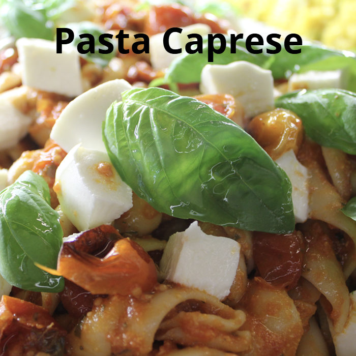 A vibrant plate of pasta caprese, featuring cooked pasta tossed with Cafe Sicilia house salad dressing, Roma tomatoes, sun-dried tomatoes, green olives, grated Parmesan cheese, diced fresh mozzarella cheese, and fresh basil leaves, garnished with whole basil leaves.