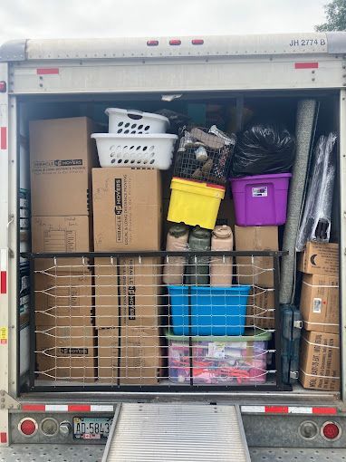 The back of a moving truck filled with boxes and baskets.