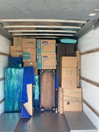 The inside of a moving truck filled with boxes and furniture.