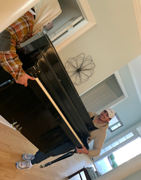 A man is standing next to a piano in a living room