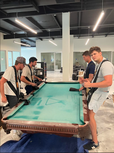 A group of men are working on a pool table.