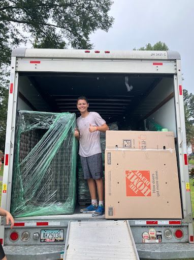 A man is standing in the back of a moving truck.