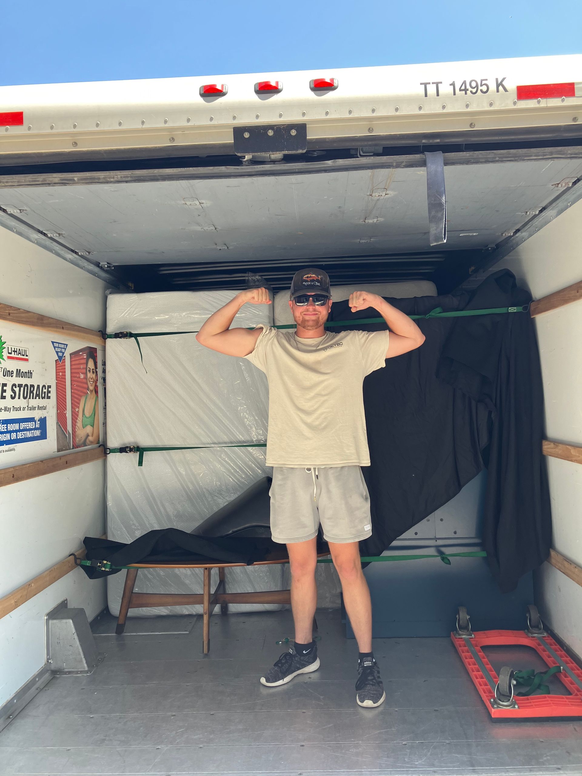 A man is flexing his muscles in the back of a truck
