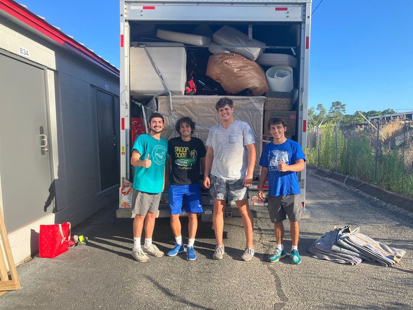 A group of young men are standing in front of a moving truck.