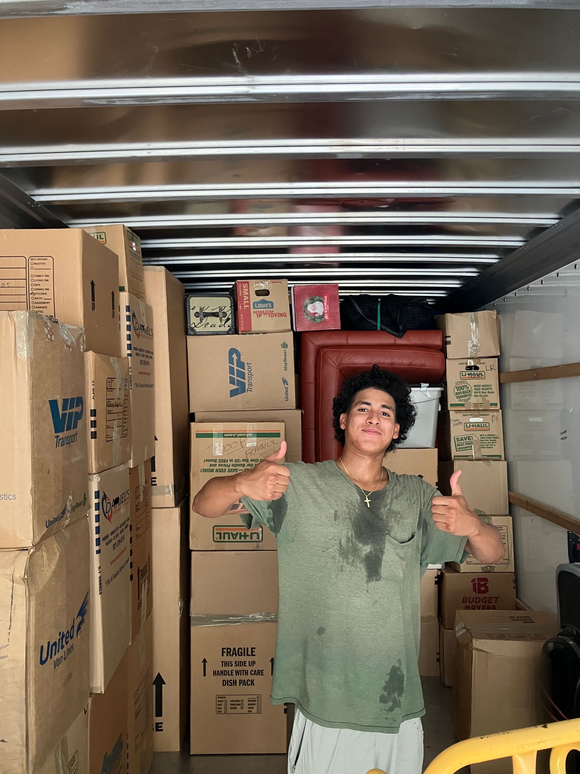 A man is giving a thumbs up in a truck full of boxes