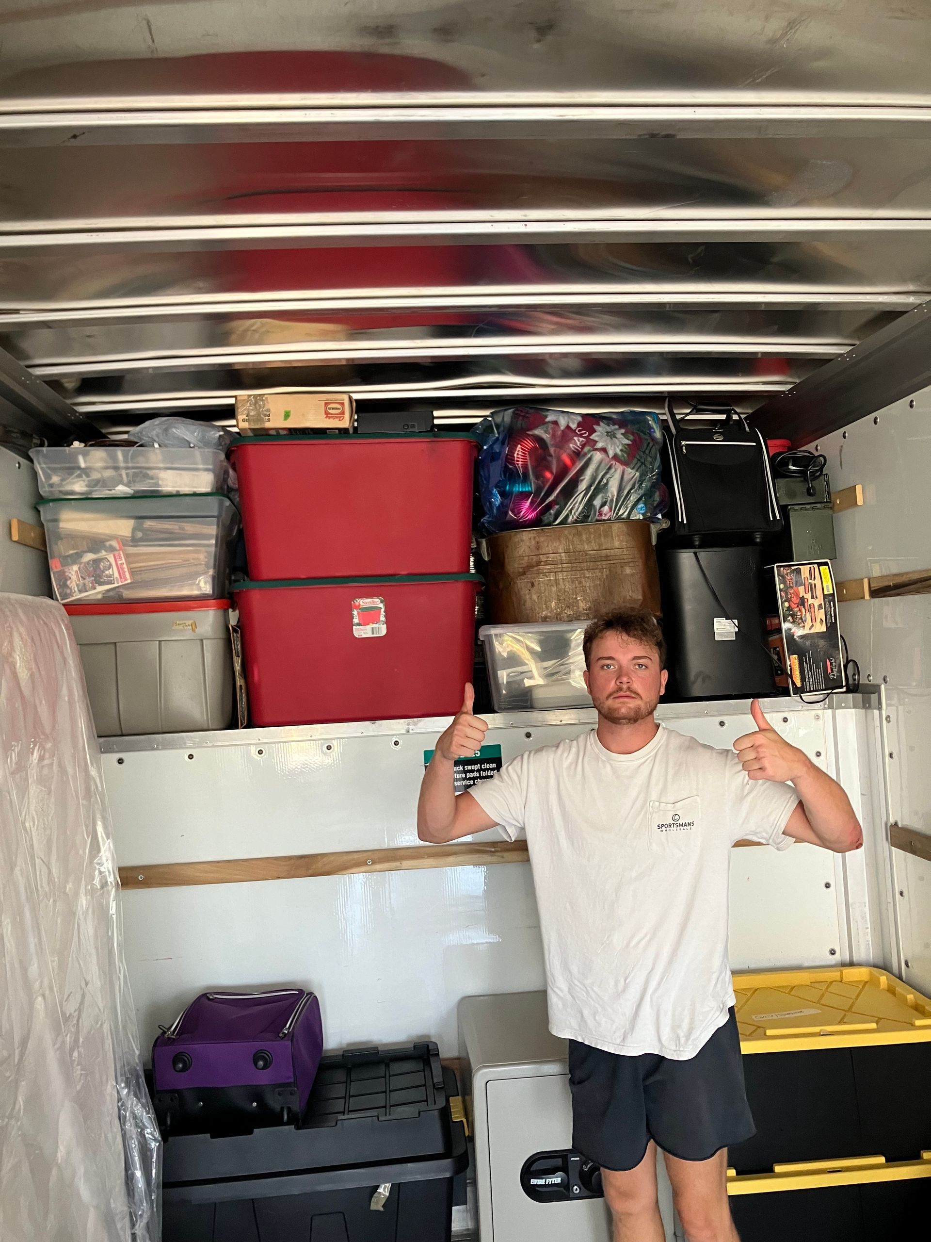 A man is standing in the back of a moving truck.