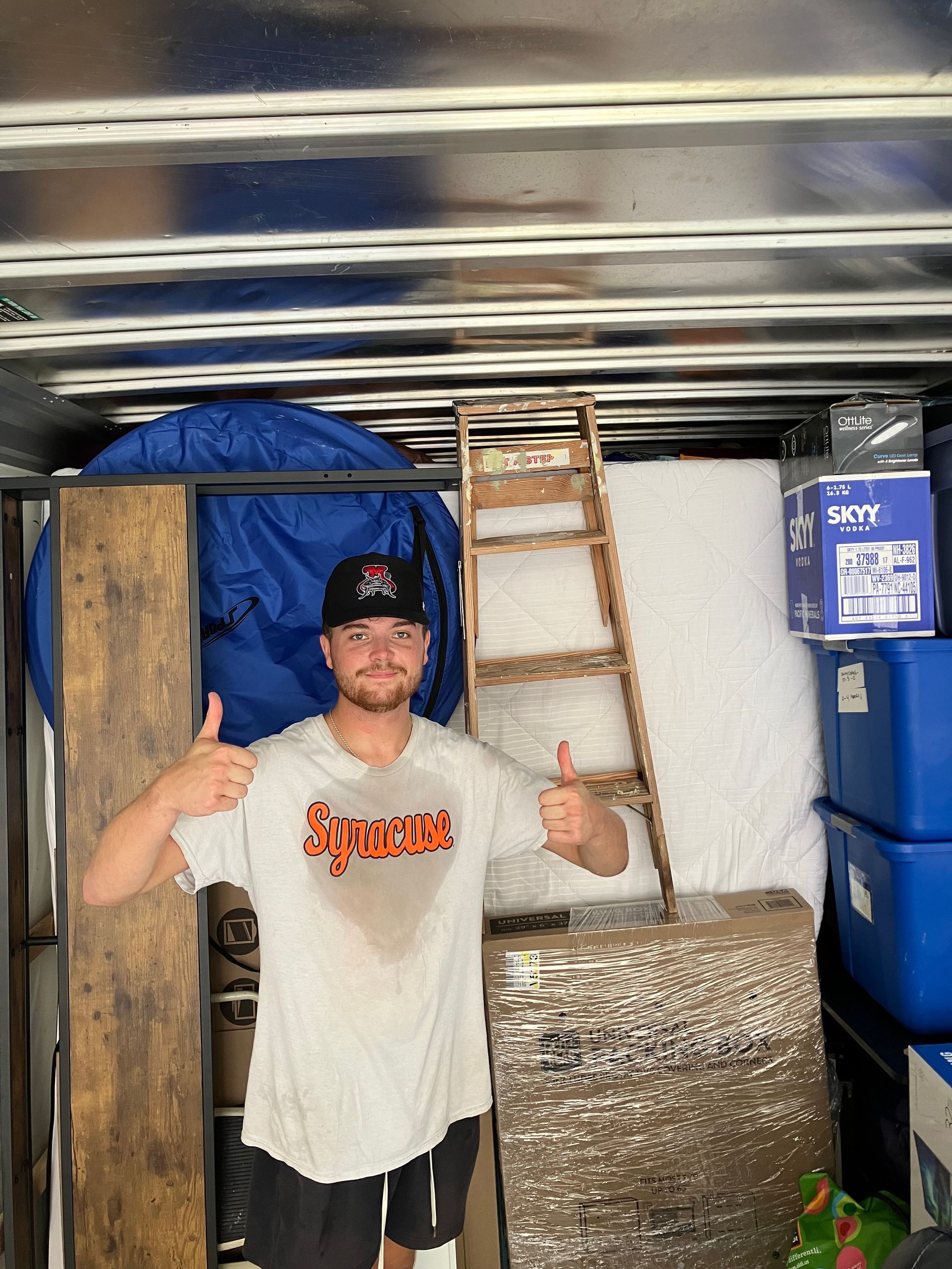A man in a supreme shirt is giving a thumbs up in a moving truck.