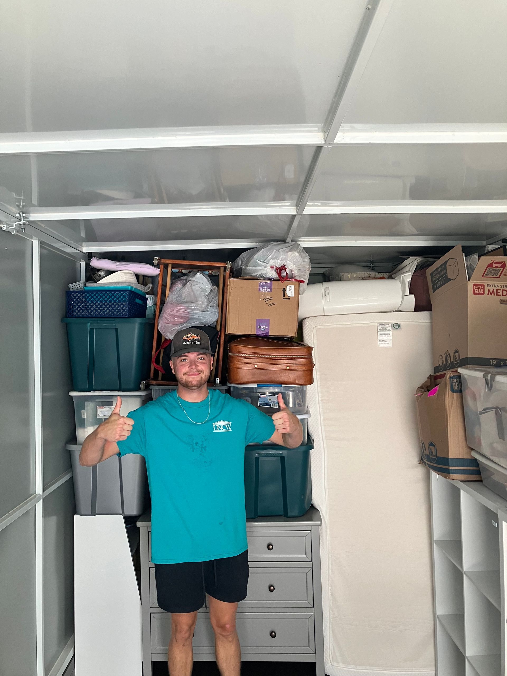 A man is standing in a trailer filled with boxes and giving a thumbs up.