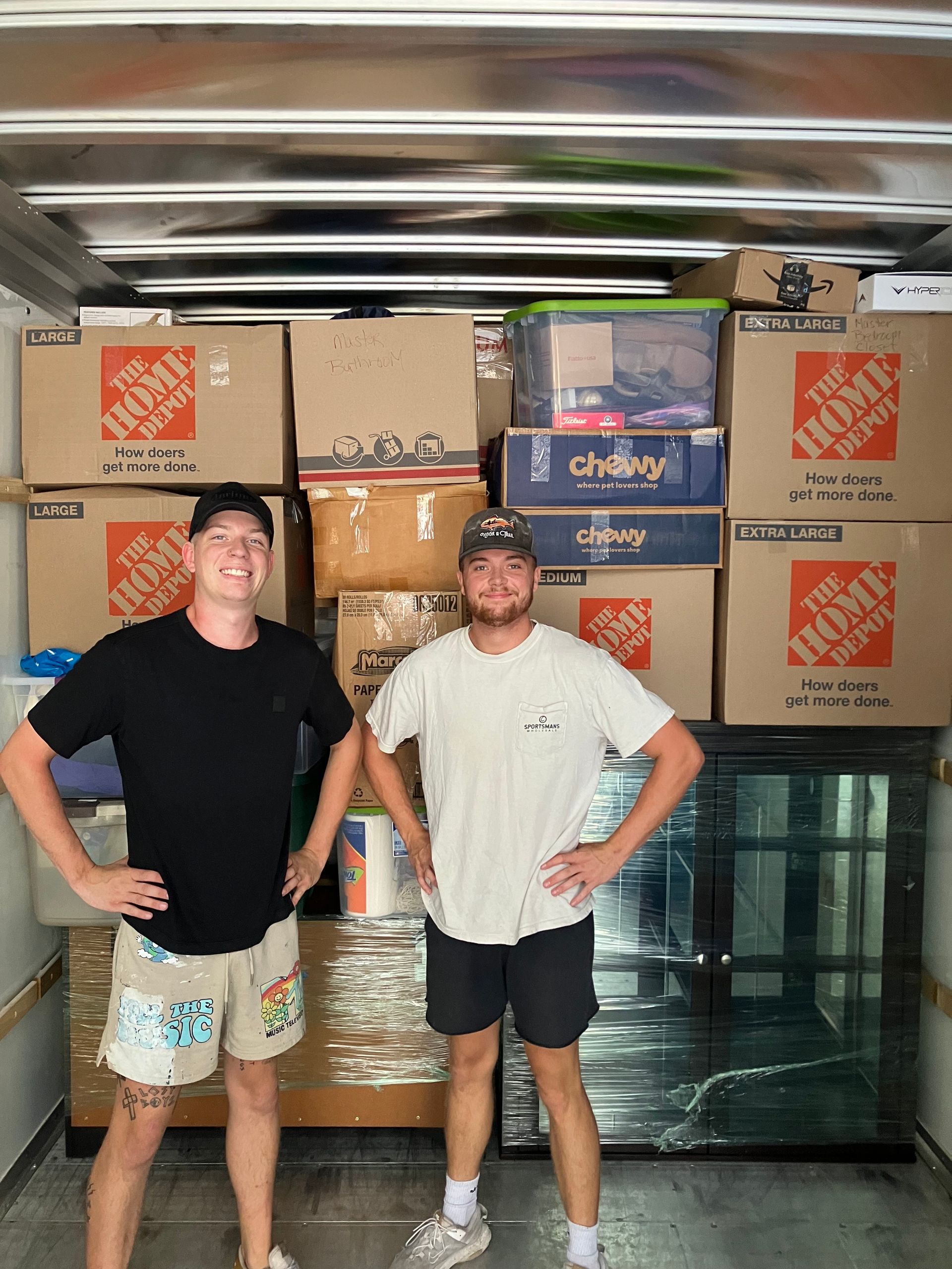 Two men are standing in the back of a home depot moving truck.