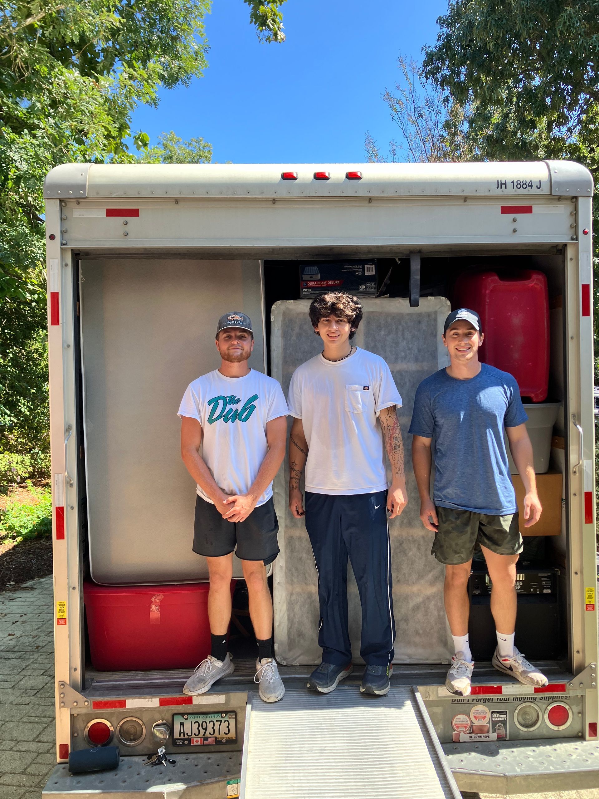 Three men are standing in front of a moving truck.