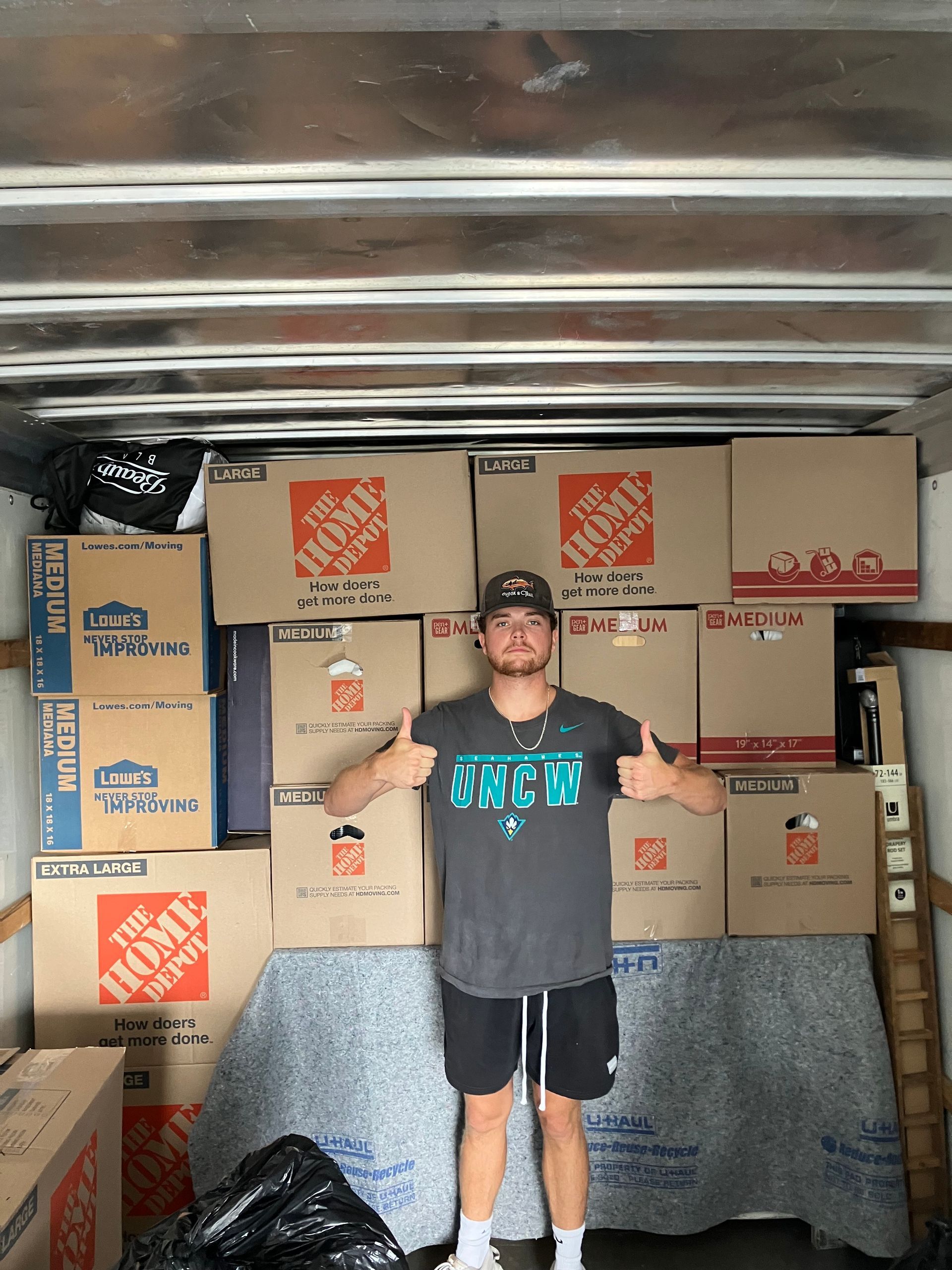 A man in a home depot shirt is standing in a moving truck