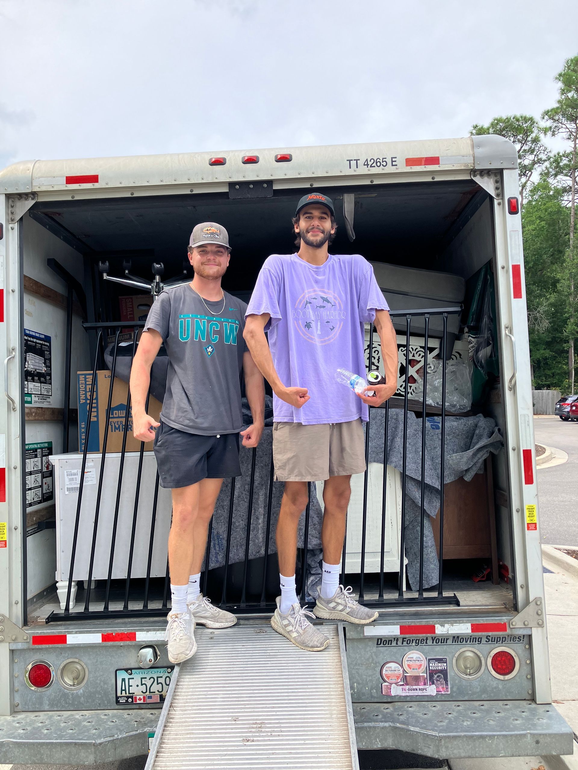Two men are standing in the back of a moving truck.