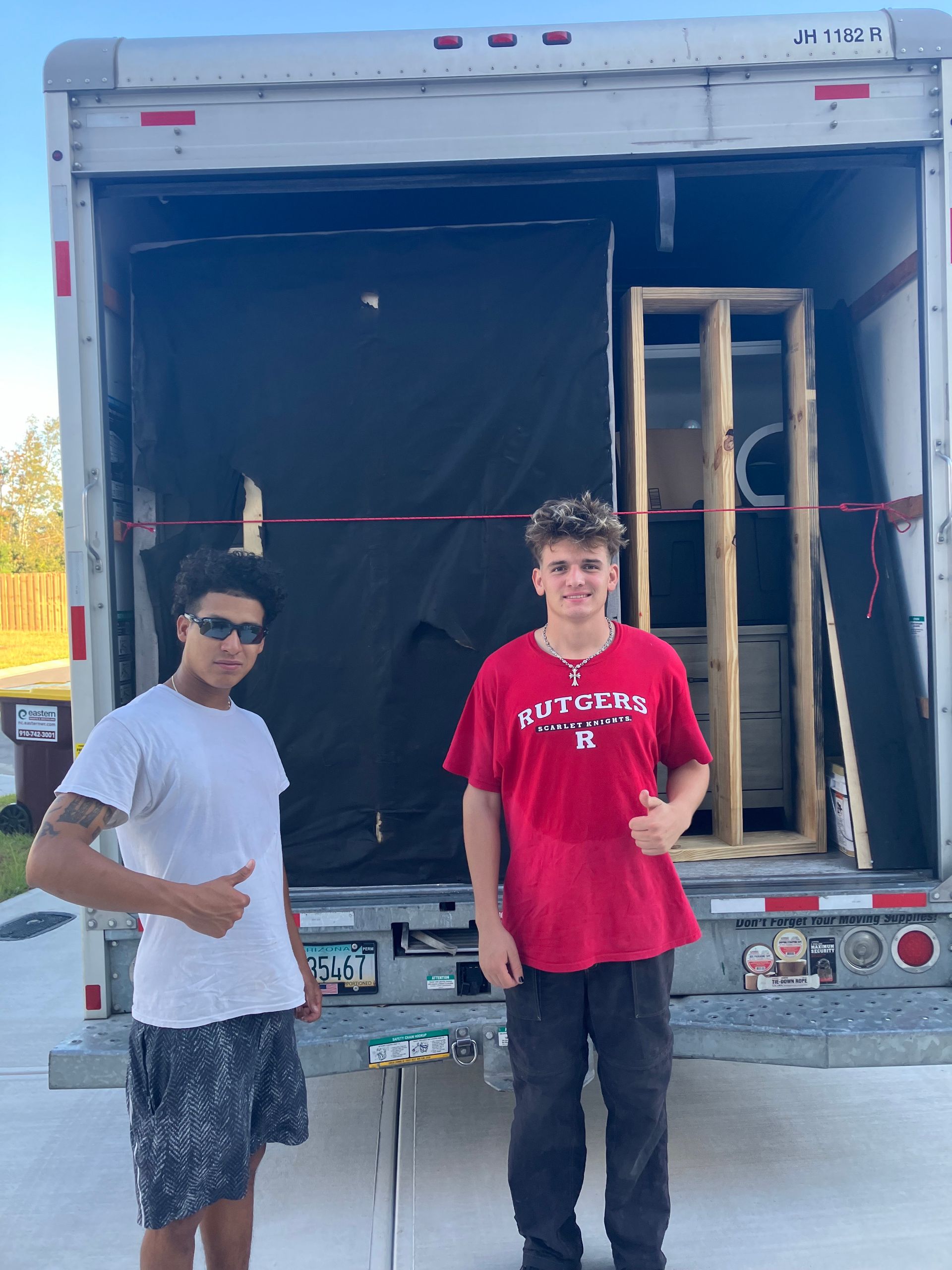 Two young men are standing in front of a moving truck