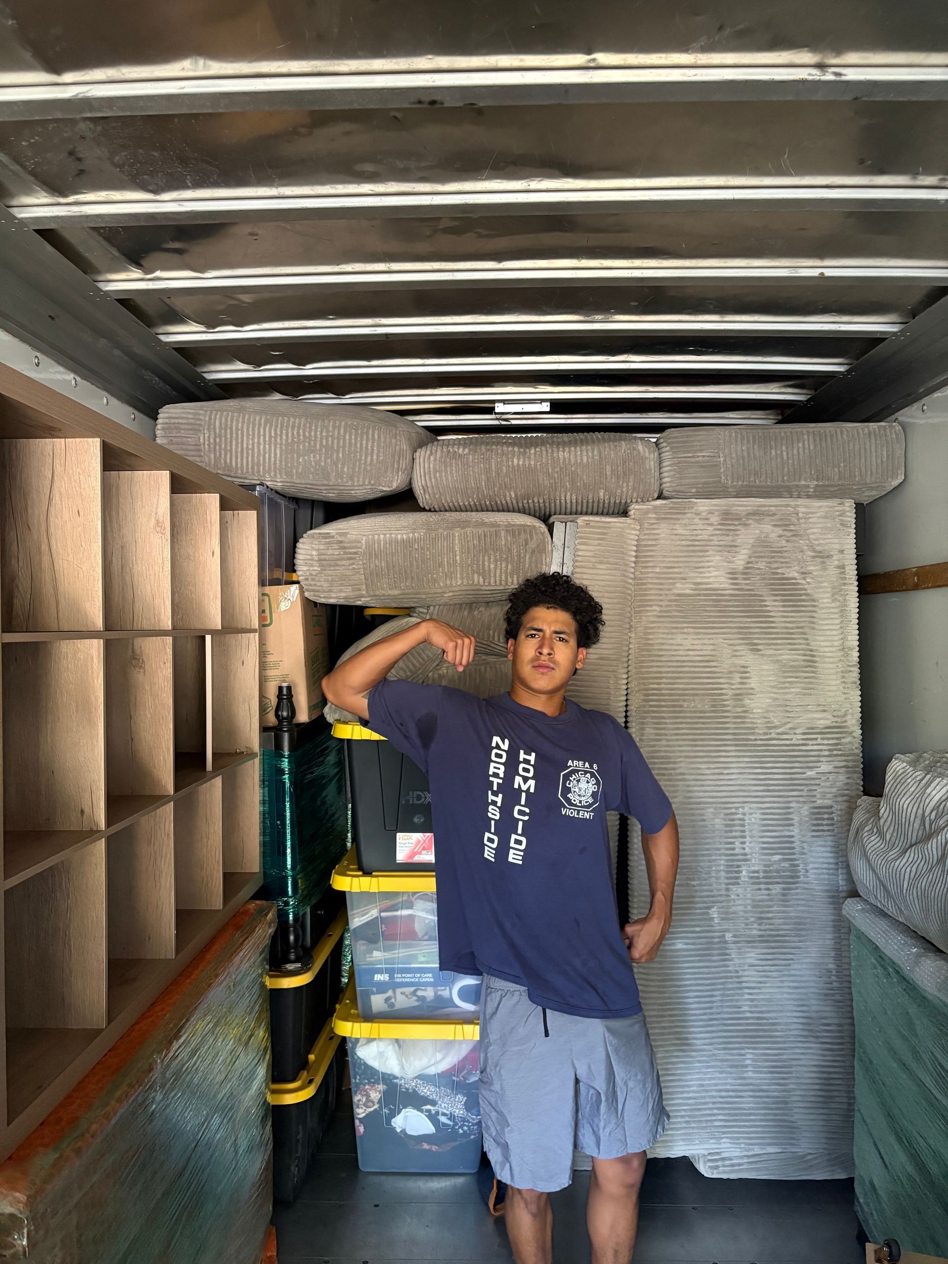 A man is standing in the back of a moving truck.