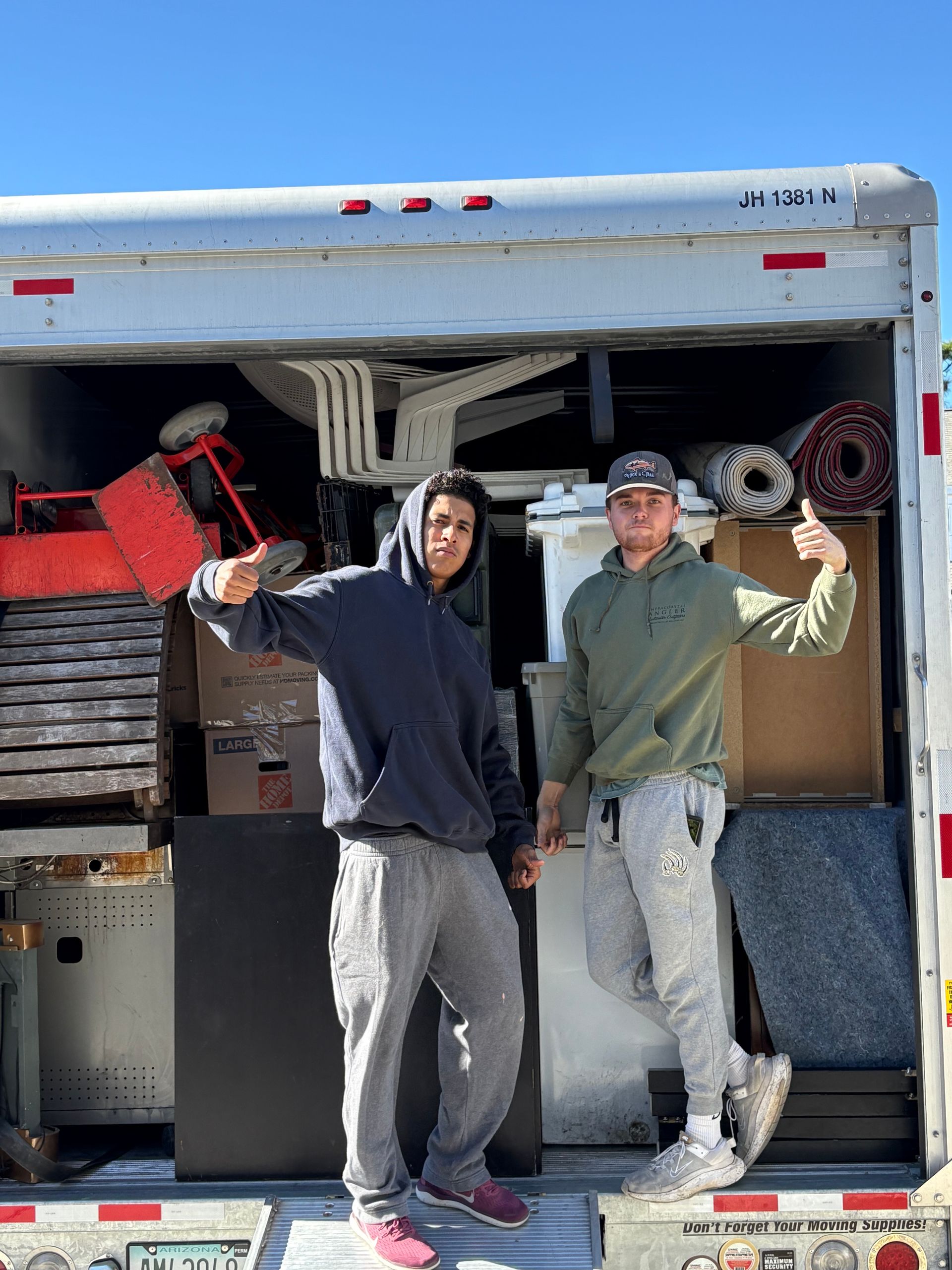 Two men are standing in front of a moving truck.