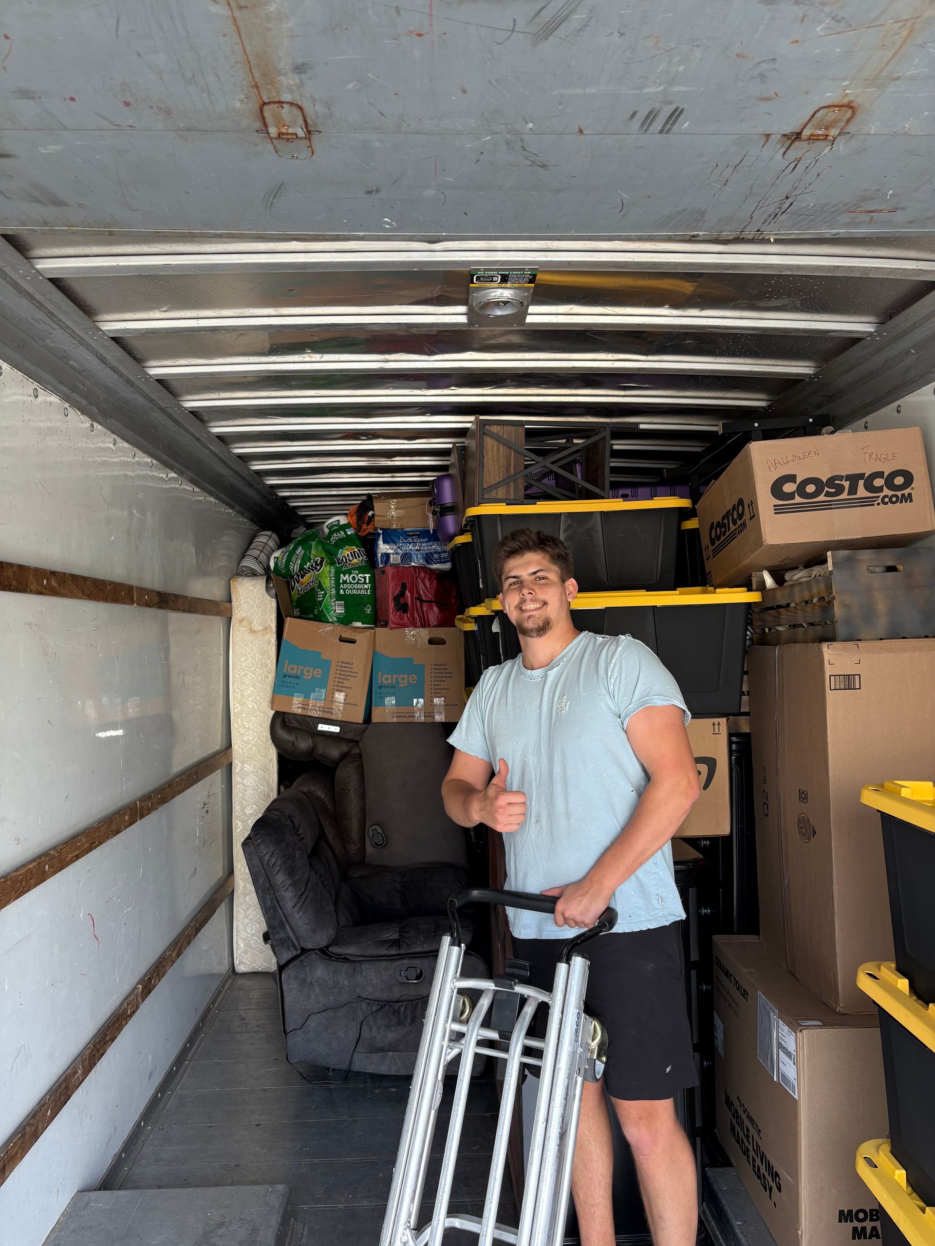 A man is standing in the back of a moving truck.