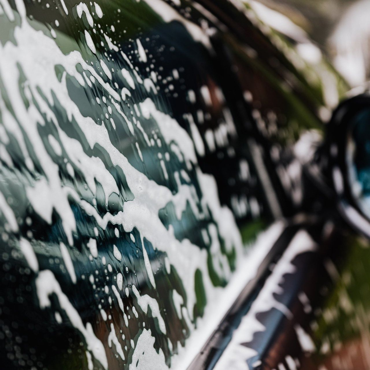 Glistening car covered in soap suds during a thorough wash.