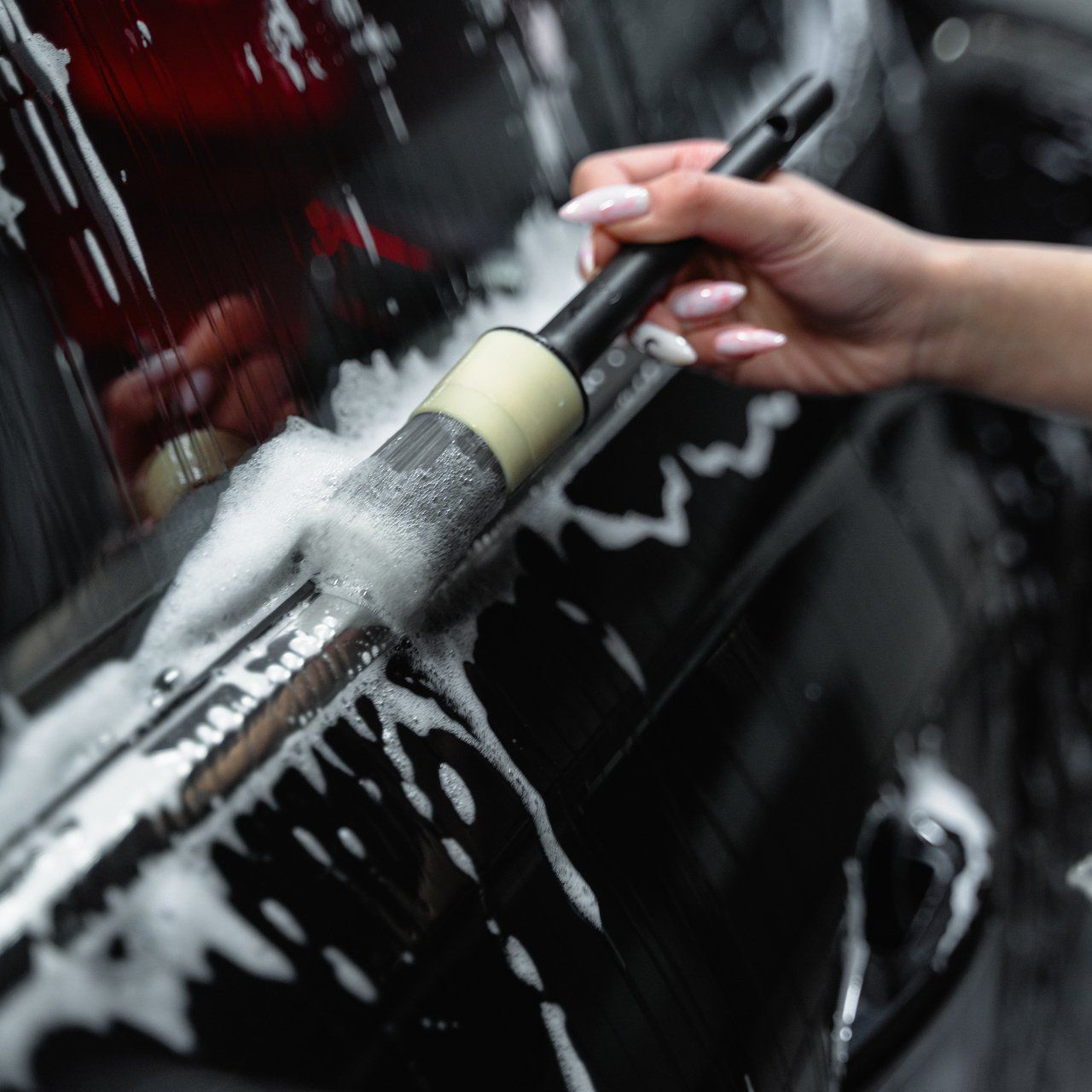 Detailer using a soft-bristled brush to meticulously clean the window edges of a car