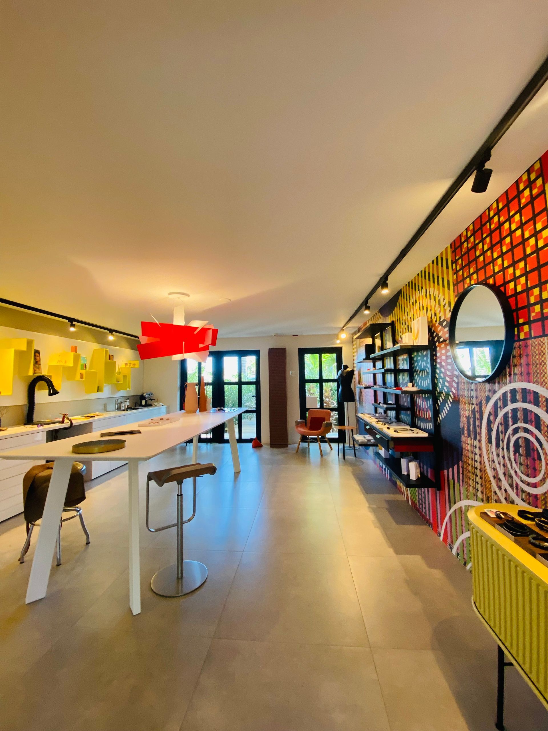 Modern interior with a white kitchen island, colorful accent wall, and track lighting.