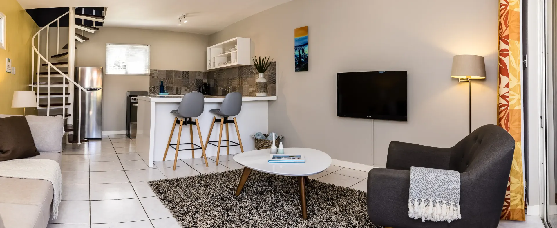 Modern apartment interior with spiral staircase, kitchen, living area, and armchair.