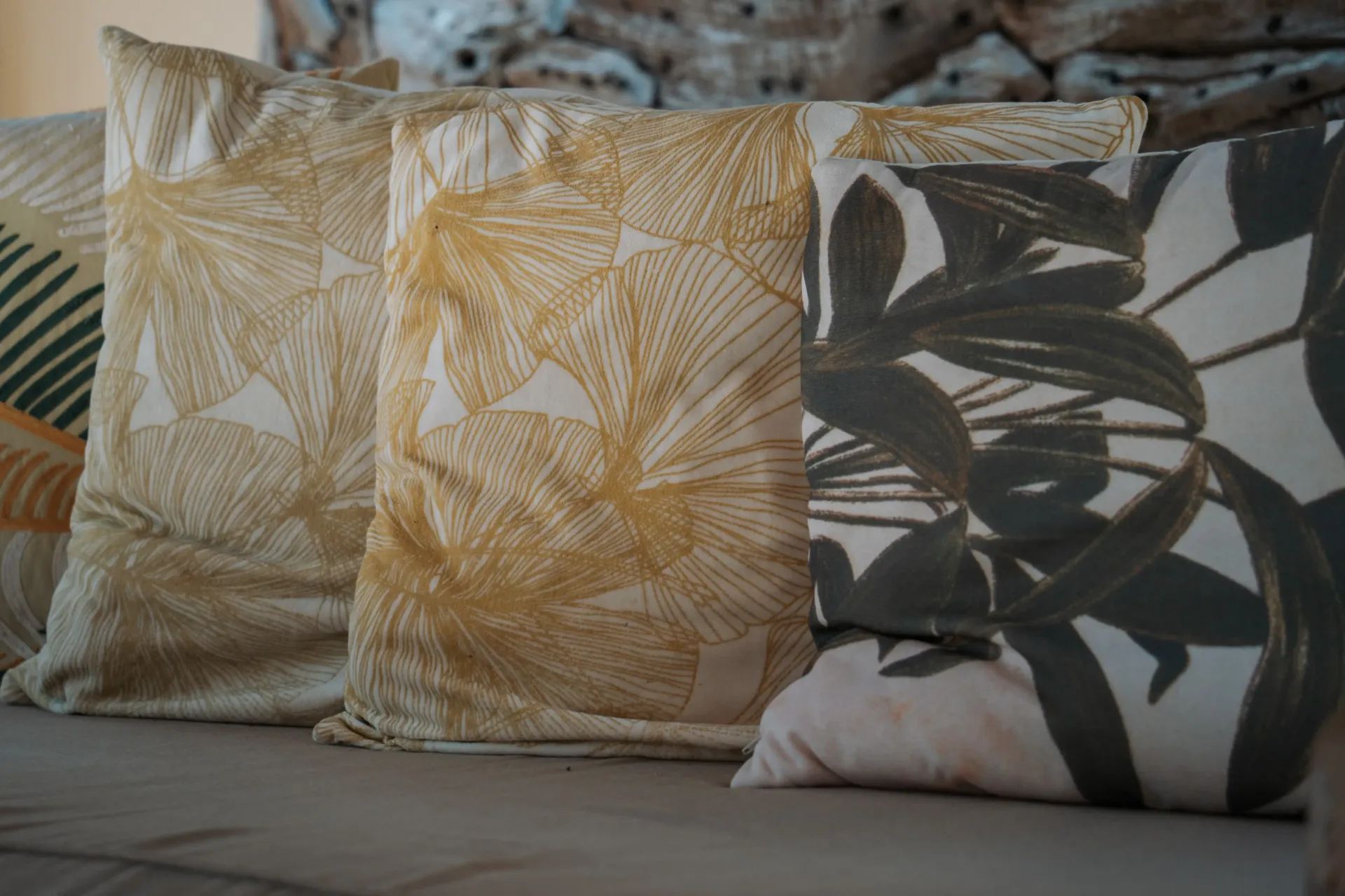 Close-up of decorative pillows with leaf patterns in shades of yellow and green on a gray surface.