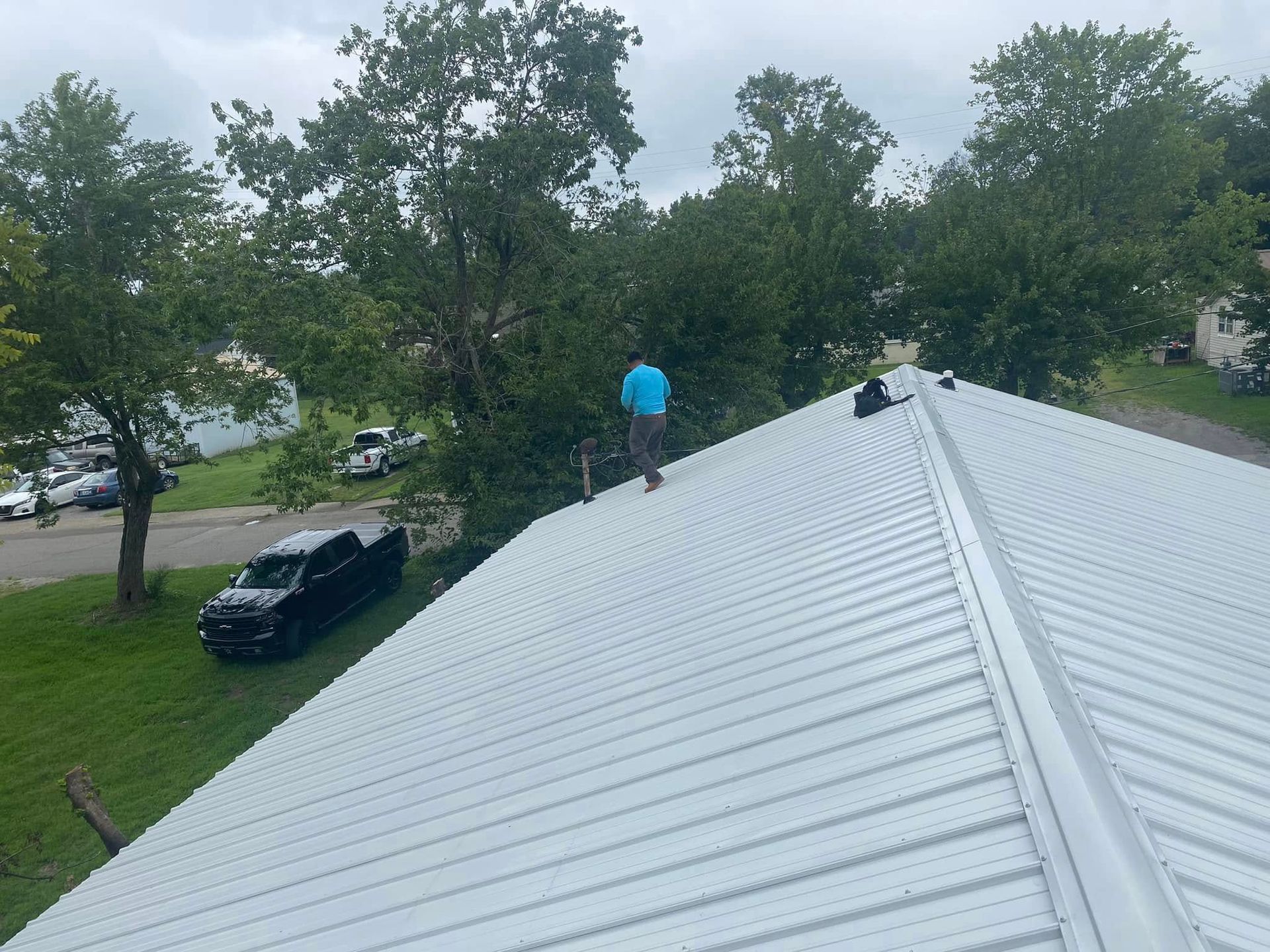 Martinez Construction | A man is standing on top of a white metal roof.