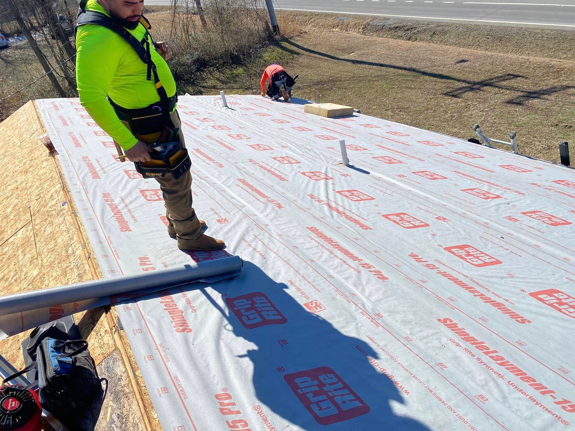Martinez Construction | A man is standing on top of a roof covered in a tarp.