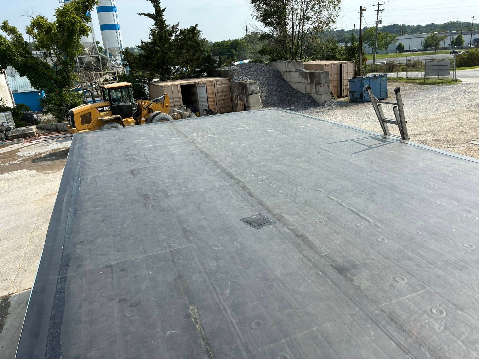 Martinez Construction | A large black roof with a yellow tractor in the background.