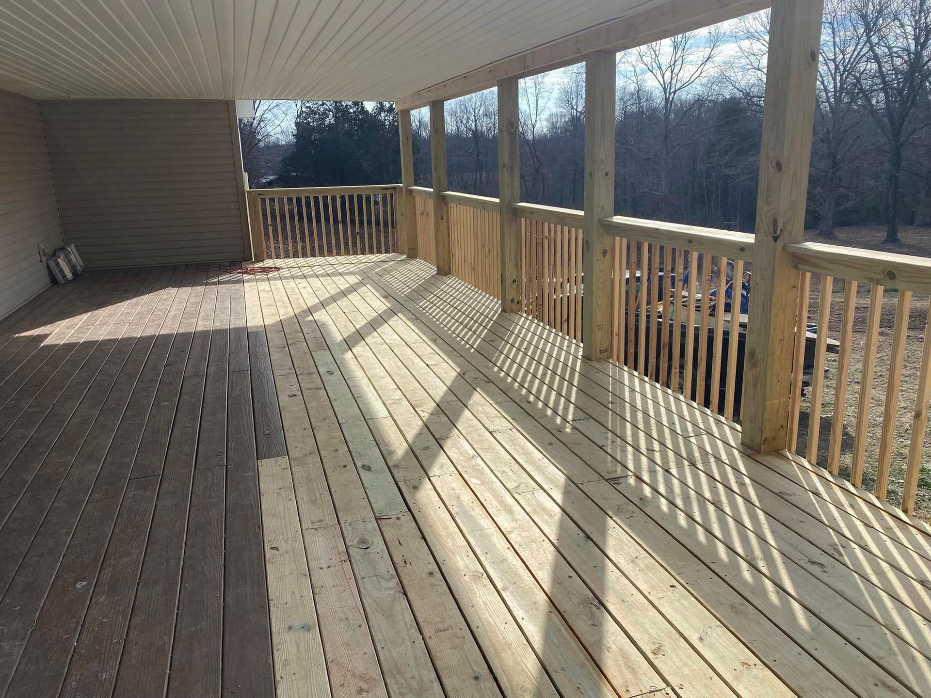 Martinez Construction | A large wooden deck with a railing and trees in the background