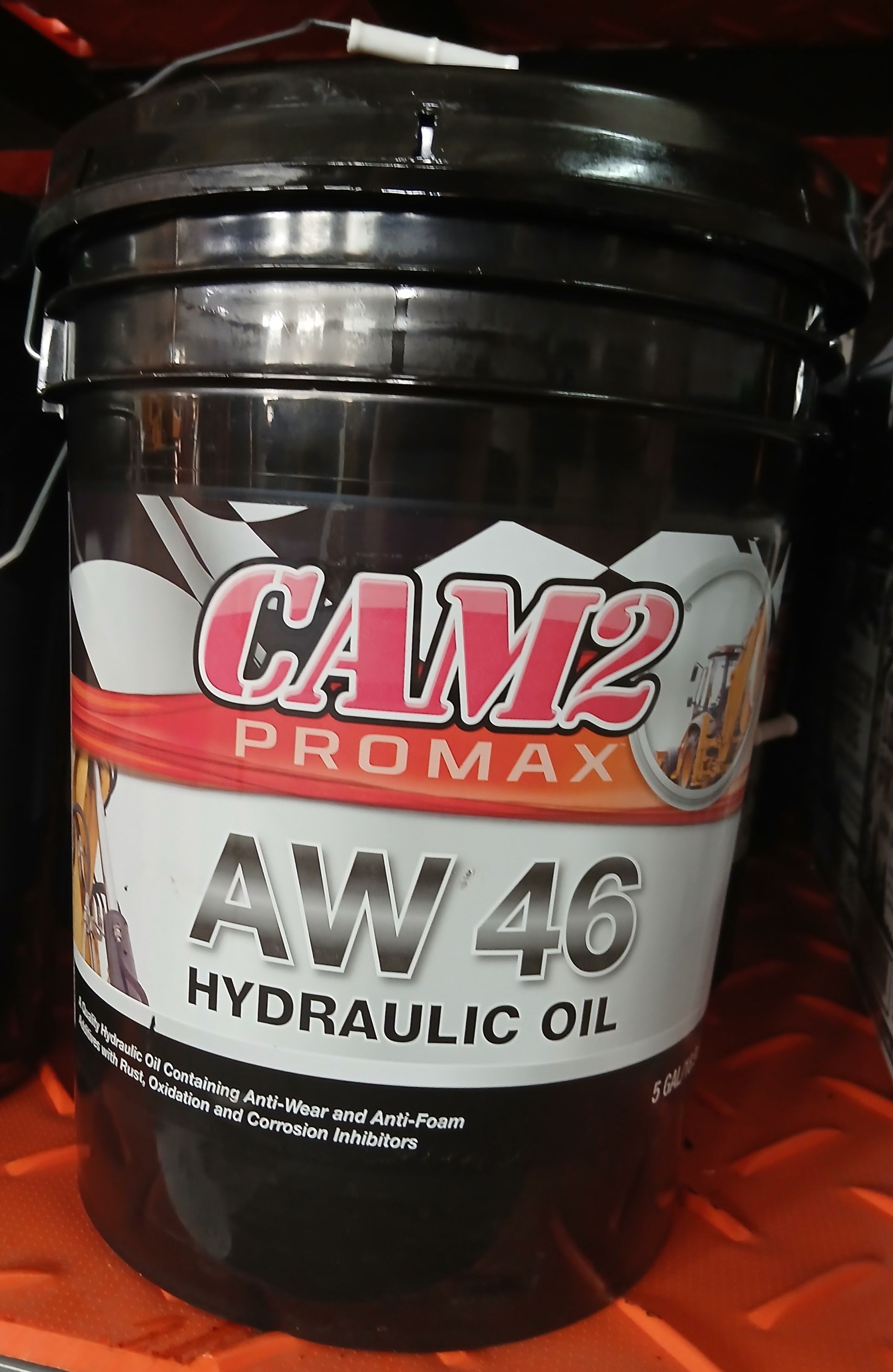 Black bucket of CAM2 PROMAX AW 46 Hydraulic Oil, with a red and white label, on a shelf.
