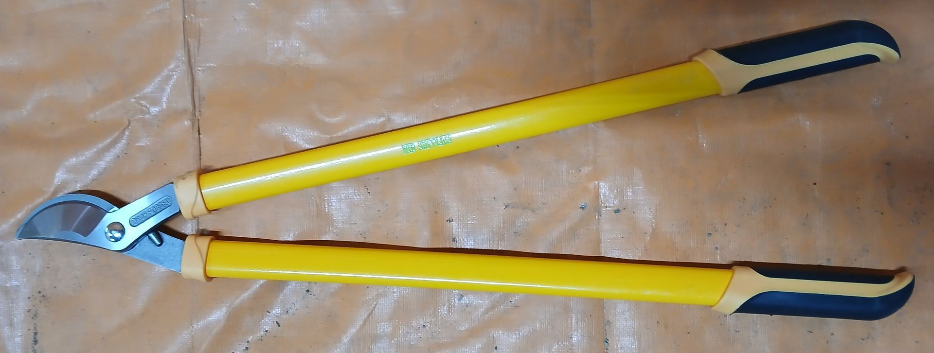 Yellow and black loppers on a light brown surface.